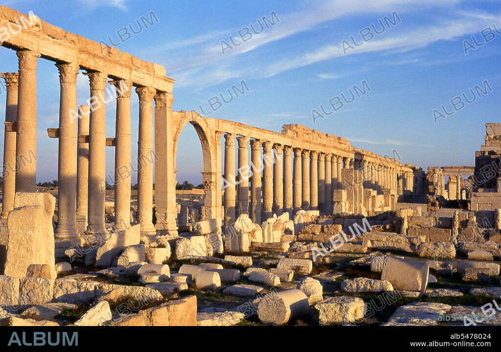Palmyra was an ancient city in Syria. It was an important city in central Syria, located in an oasis 215 km northeast of Damascus and 180 km southwest of the Euphrates at Deir ez-Zor. It had long been a vital caravan city for travellers crossing the Syrian desert and was known as the Bride of the Desert. The earliest documented reference to the city by its Semitic name Tadmor, Tadmur or Tudmur (which means 'the town that repels' in Amorite and 'the indomitable town' in Aramaic) is recorded in Babylonian tablets found in Mari.
