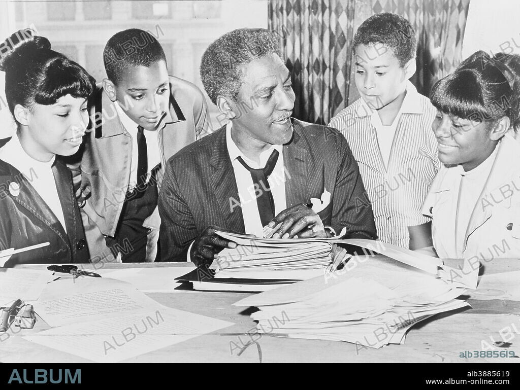 Bayard Rustin (center) speaking with (left to right) Carolyn Carter, Cecil Carter, Kurt Levister, and Kathy Ross, before demonstration, 1964.