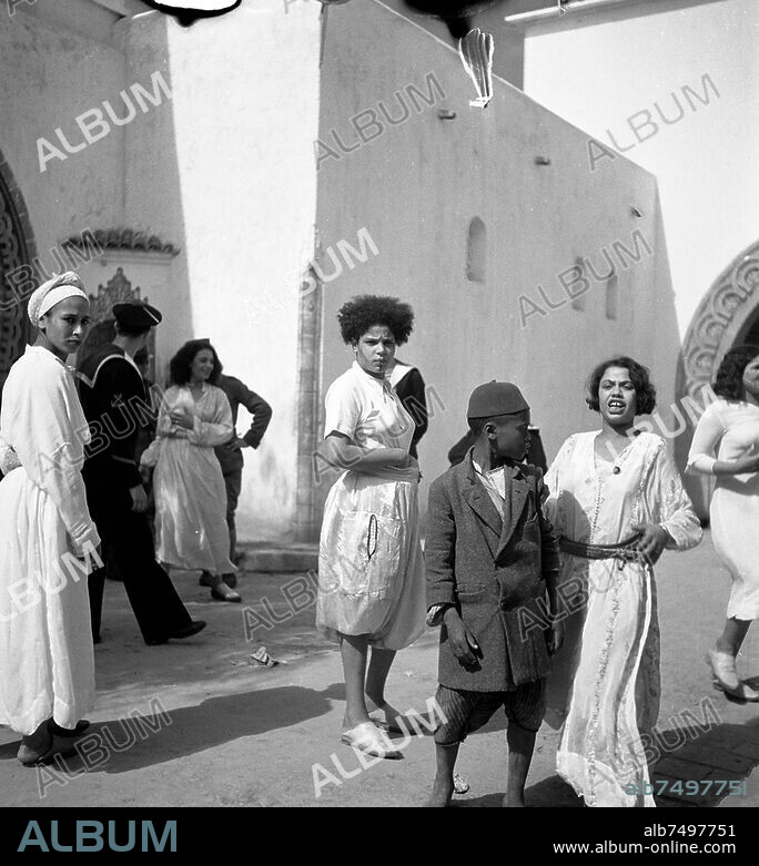 Sexualité / Prostitution. A Casablanca (Maroc), le quartier du Bousbir (Enceinte fortifiée de Casablanca, construite pour accueillir le "quartier réservé" à la prostitution de la ville. Quand le Maroc devient un protectorat français par le traité de Fès en 1912, les autorités voulurent lutter contre la propagation des infections sexuellement transmissibles, en particulier la syphilis parmi les troupes militaires stationnées dans le protectorat. Elles mettent alors en place des quartiers réservés et organisent la prostitution en la réglementant et en la réservant à certains secteurs). Prostitution dans les rues du Bousbir. Scènes de rue avec prostituées et marins français, portraits d'habitants du Bousbir. Photo de Denise Bellon (1902-1999), avril 1936. Tiré d'un reportage sur le Maroc.
