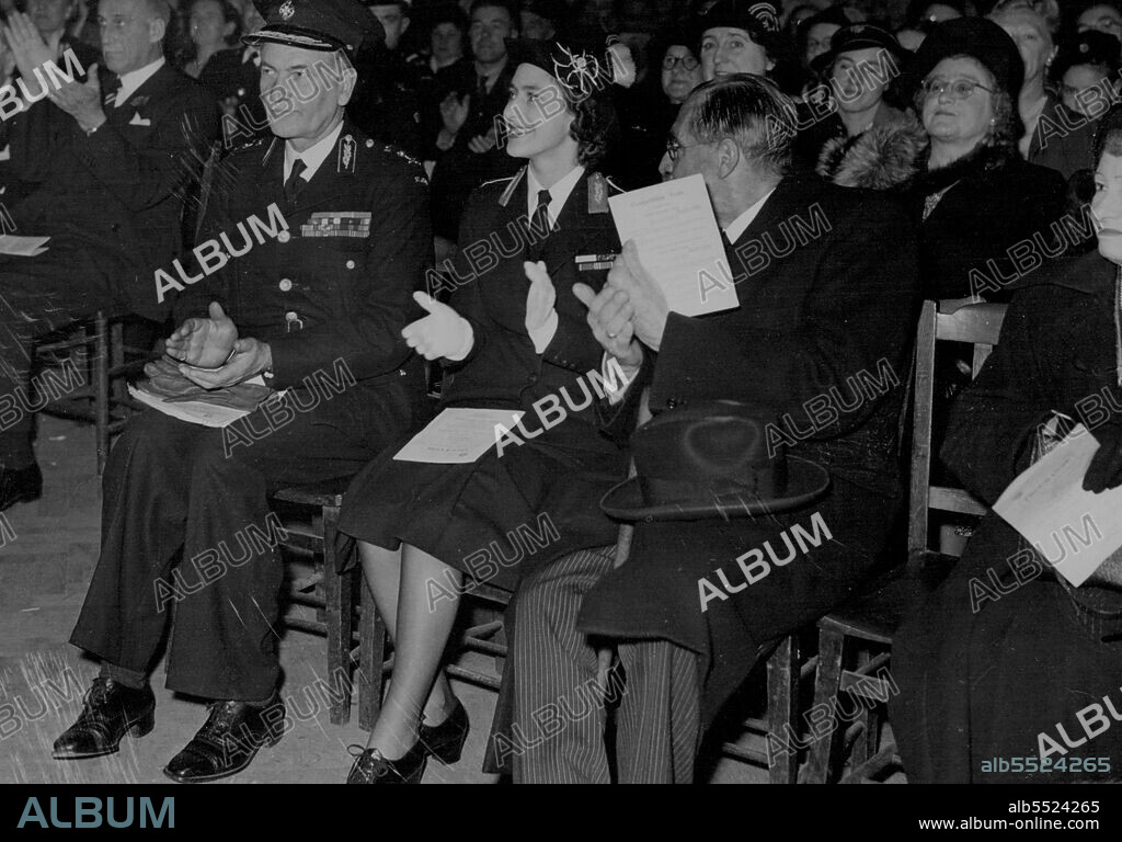 Princess Sees St. John Ambulance Competitions -- Princess Margaret, wearing the uniform of Commandant-in-Chief of the St.John Ambulance and Nursing Cadets, applauding one of the teams of Cadets then they competed for trophies it the Finals of the National First Aid and Home Nursing Competitions at the Central Hall, Westminster here. Forty-three teams from twenty-two English counties, Wales and Northern Ireland, competed for the challenge shields, cups and various prizes which were presented by the Princess. On left is Lieut-General Sir Henry Pownall, Chief Commissioner of the force. November 6, 1949. (Photo by Plant News Ltd.).