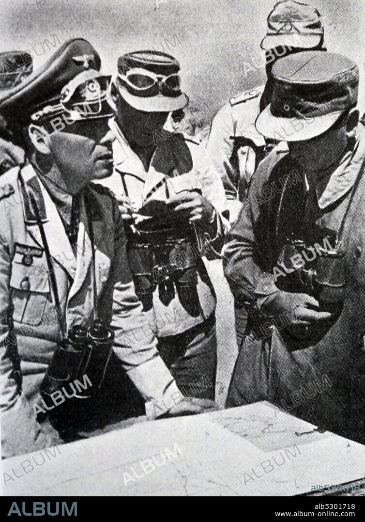 Black and white photograph of World War II (1939-1945); German general Erwin Rommel (1891-1944), Commander of the African Corps, standing over a map instructing his officers.