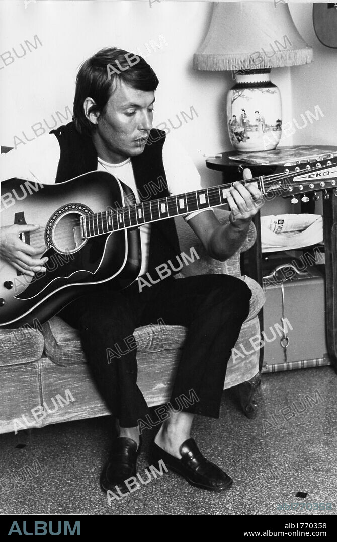 Fabrizio De Andre with the guitar. The Italian singer-songwriter Fabrizio De Andre playing the guitar sitting on the couch. 1970s.