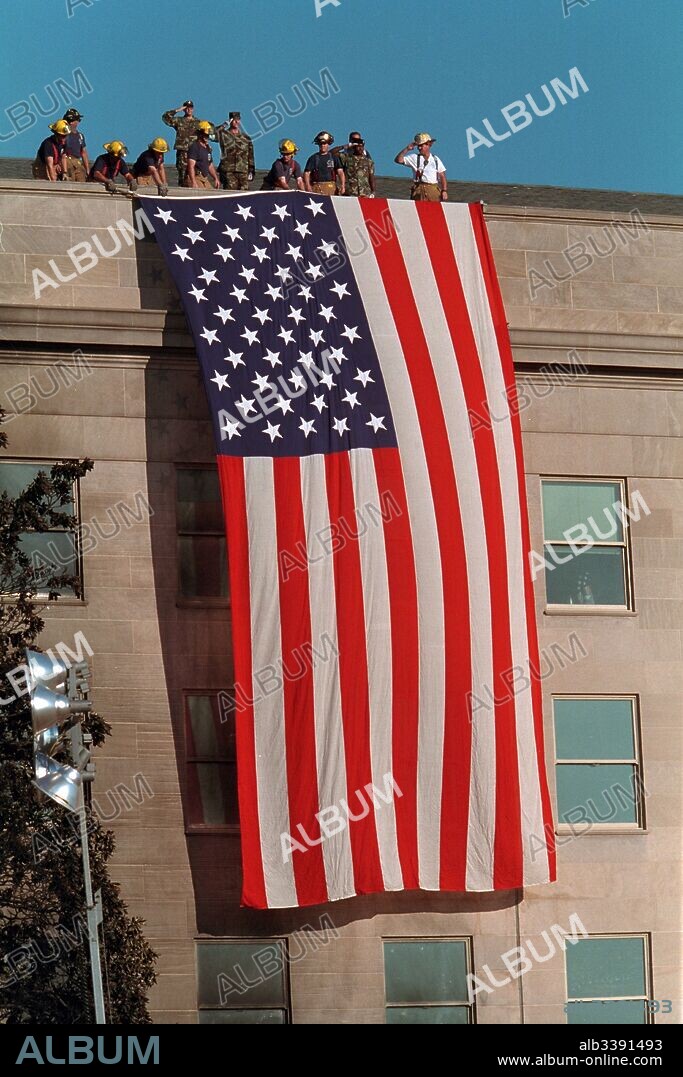 Firefighters unfurl an American flag over the Pentagon following the September 11 terrorist attacks, Arlington, Virginia, September 12, 2001.
