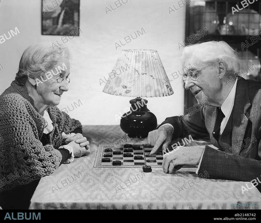 Mature adult couple playing game of checkers.