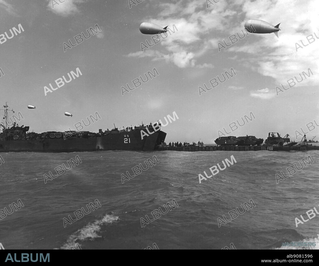 WW2: Protected from straffing Nazi planes by barrage balloons, a coast guard tank landing ship (left) forward passes a load of mechanised fighting vehicles to flat top of a "rhino" in the English in the English Channel during the height of the invasion of the French coast. The "Rhinos" slogged through the surf to unload their cargoes on the beach.