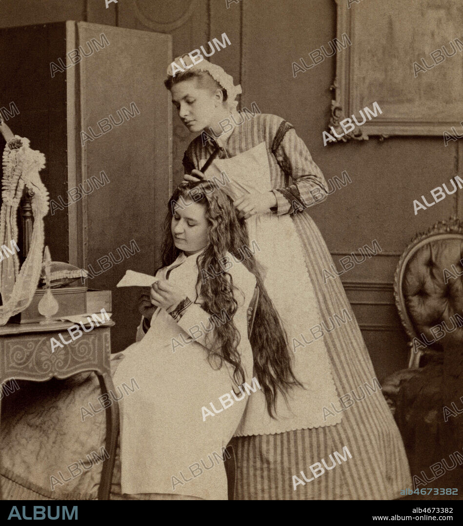 Femme se faisant coiffer les cheveux par sa domestique sous le second Empire, la femme lit une lettre, la bonne lit la lettre par dessus son epaule.. 19eme siecle. Collection Avant-Demain/KHARBINE-TAPABOR.