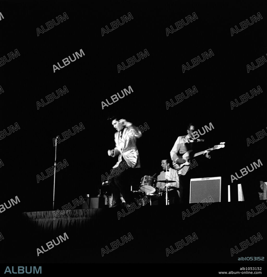 American singer Elvis Presley during a concert at Pan Pacific Stadium in November 1957 with the American guitarist Scotty Moore and the American bassist Bill Black.