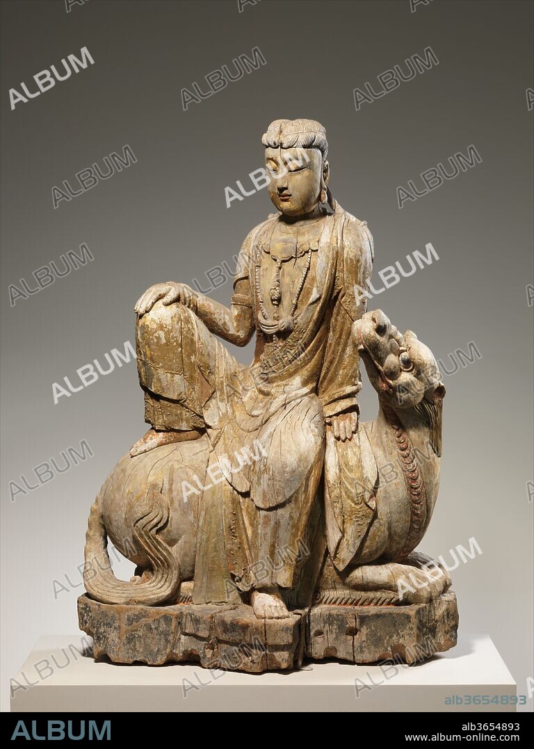 Bodhisattva Avalokiteshvara of the Lion's Roar, or Simhanada Avalokiteshvara (Shi Hou Guanyin). Culture: China. Dimensions: H. 42 1/8 in. (107 cm); W. 29 in. ( 73.7 cm); D. 13 in. (33 cm). Date: late 15th-early 17th century.
Avalokiteshvara (the Bodhisattva of Compassion) and Manjushri (the Bodhisattva of Wisdom) are identifiable by the fact that both, at times, appear atop lions. As such, they are said to assume the form of Simhanada, or the Lion's Roar, which is a reference to the intensity of the moment of enlightenment. Here, the lion's recumbent pose and the bodhisattva's sidewise posture suggest that this sculpture represents Simhanada Avalokiteshvara, although the headdress does not bear the image of a seated Buddha, which is Avalokiteshvara's standard identifying attribute. Depictions of Simhanada Avalokiteshvara developed in India around the eleventh or twelfth century and appeared in China during the twelfth.